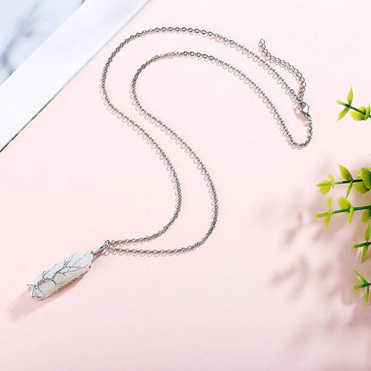 Silberne Halskette mit weißem Marmoranhänger auf rosa Hintergrund, eleganter Schmuck.