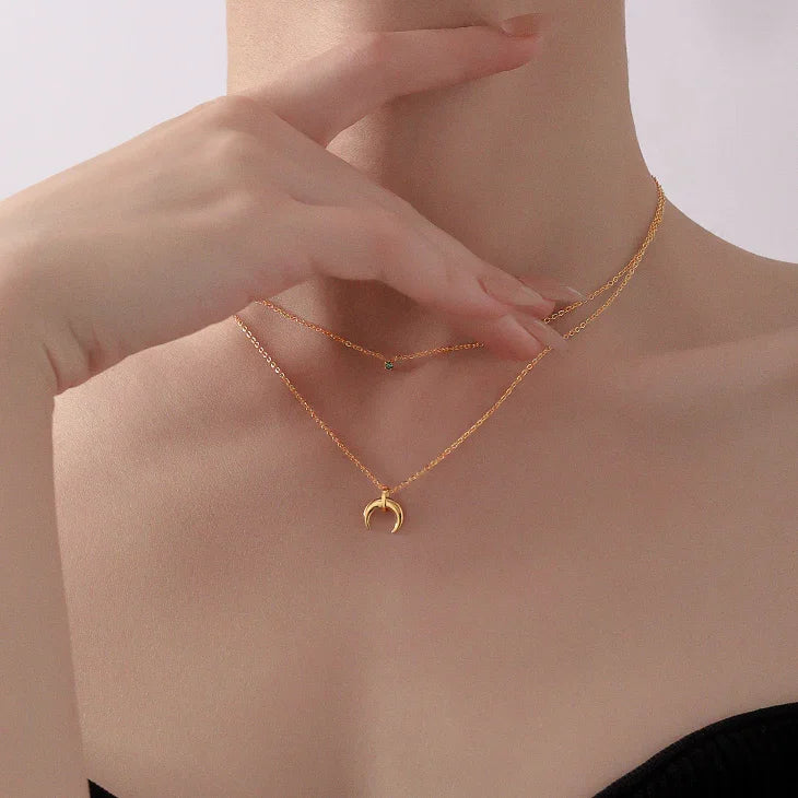 Frau trägt goldene Halskette mit Halbmond-Anhänger, eleganter Schmuck, minimalistisch.