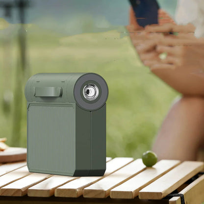 Grüner tragbarer Mini-Projektor auf Holztisch im Freien, kompakt und modern.