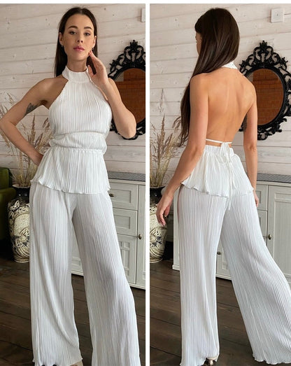 Frau in weißem, ärmellosem, plissiertem Jumpsuit mit offenem Rücken, elegantes Design.