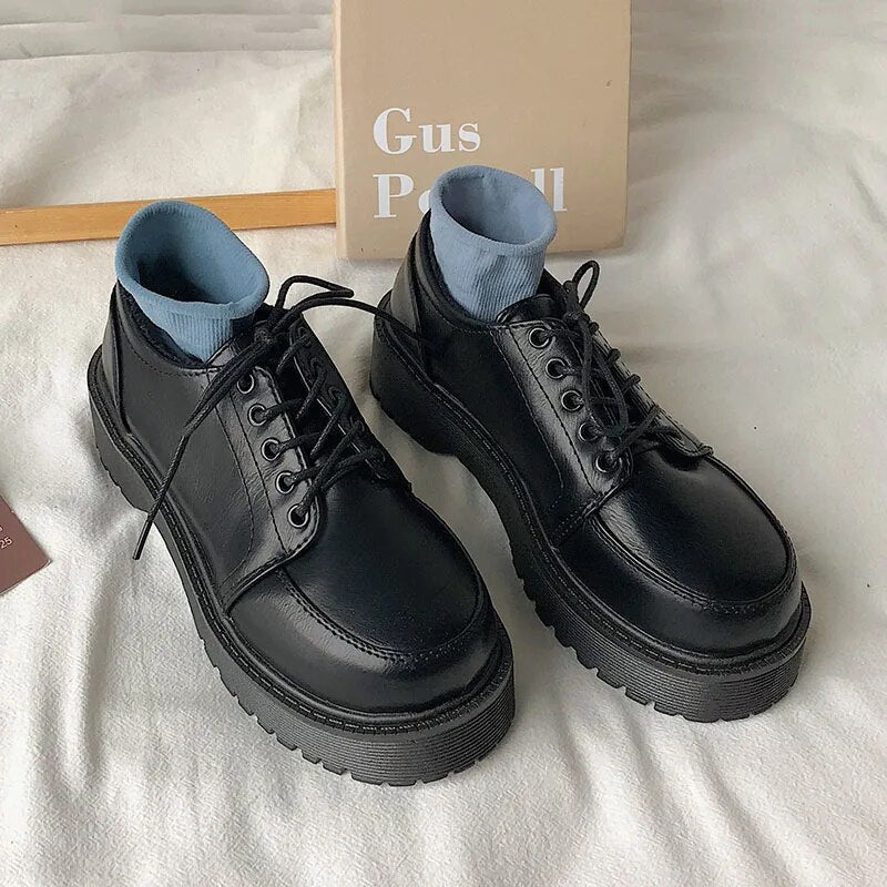 Schwarze Leder-Schnürschuhe mit dicker Sohle auf weißem Hintergrund, modisch und robust.