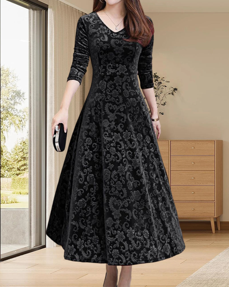 Frau in elegantem schwarzem Samtkleid mit Muster, V-Ausschnitt, 3/4-Ärmeln, in modernem Wohnzimmer.