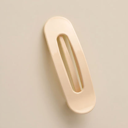 Blank krämfärgad hårklämma med avlång öppning, fotograferad snett uppifrån mot ljus bakgrund 7