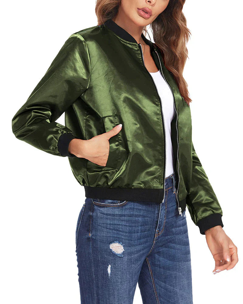 Frau in grüner Satin-Bomberjacke, schwarze Bündchen, weiße Bluse, zerrissene Jeans.