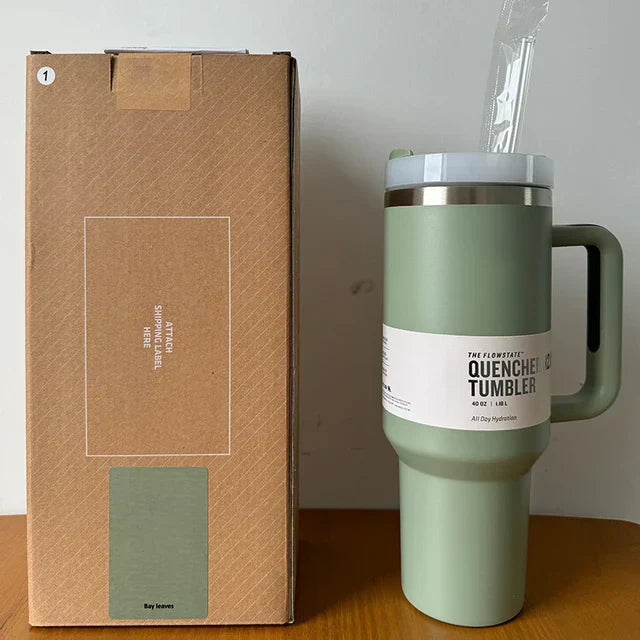 Grüner Edelstahl-Thermobecher mit Griff, 1,2L, neben brauner Verpackung, ideal für unterwegs.