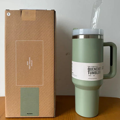 Grüner Edelstahl-Thermobecher mit Griff, 1,2L, neben brauner Verpackung, ideal für unterwegs.