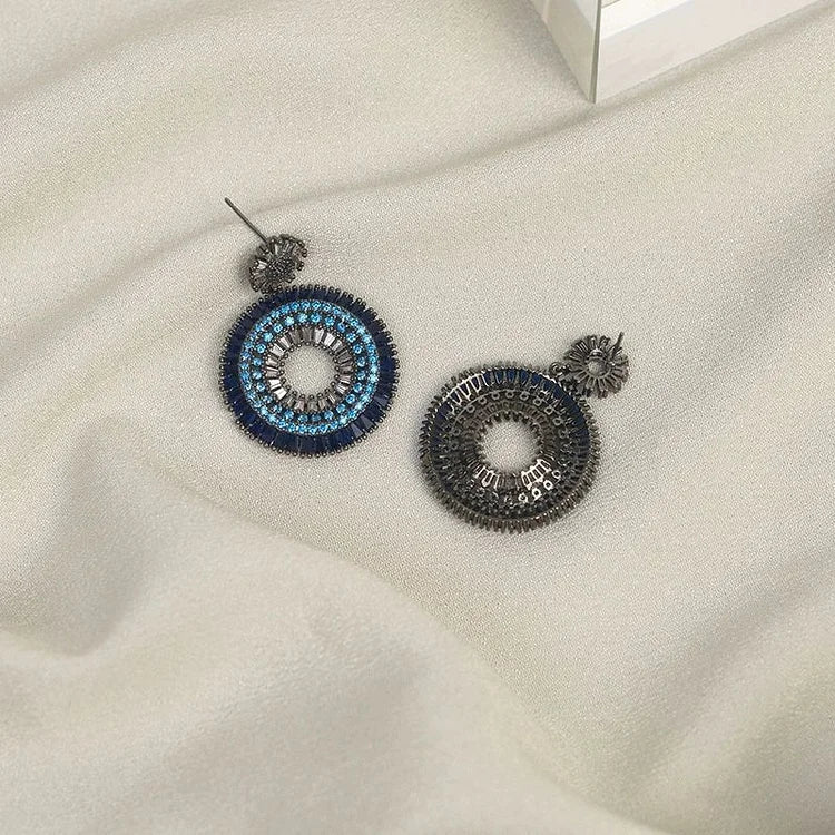 Blaue und silberne Ohrringe auf beigem Stoff, handgefertigter Schmuck, modisches Accessoire.