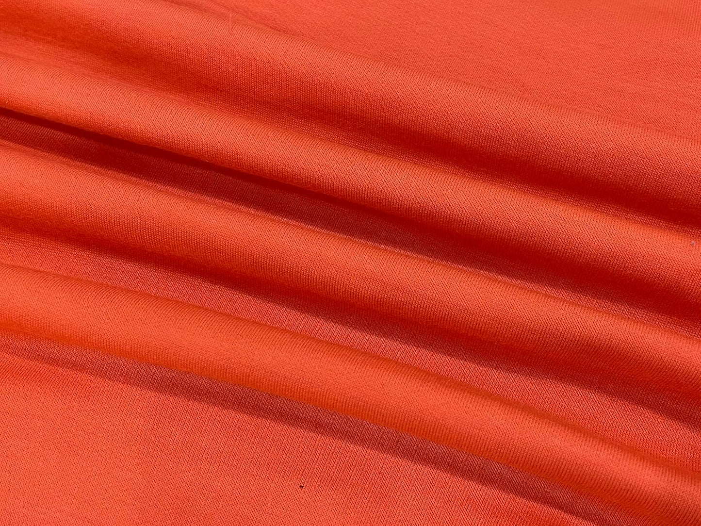 Orangefarbener Baumwollstoff, weicher Textilstoff, ideal für Kleidung und Dekoration.