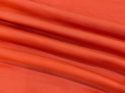 Orangefarbener Baumwollstoff, weicher Textilstoff, ideal für Kleidung und Dekoration.