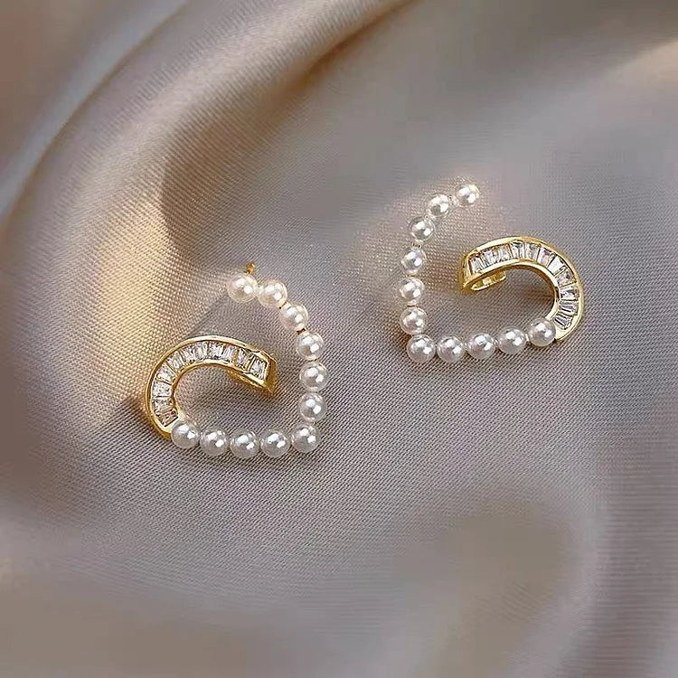 Goldene Ohrringe mit Perlen und Kristallen auf Seide, eleganter Schmuck, luxuriöses Design.