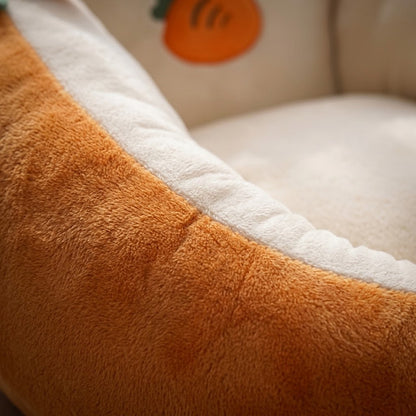 Närbild på den orangea och gräddvita plyschens mjuka yta och söm, med brodd morot i bakgrunden 2