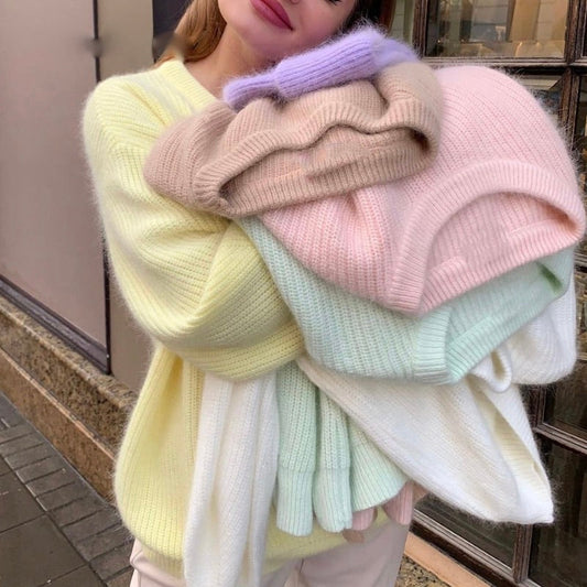 Frau hält bunte Strickpullover aus Wolle, pastellfarben, gemütliche Wintermode, Straßenhintergrund.