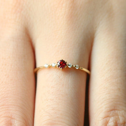 Dünner Goldring mit rotem Edelstein und kleinen Diamanten, eleganter Schmuck für Damen.