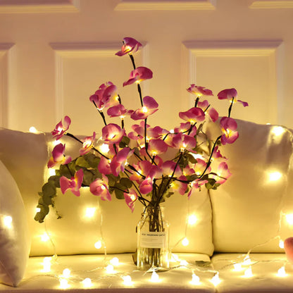 Künstliche rosa Orchideen in Vase mit Lichterkette, Wohnzimmerdekoration, stimmungsvolle Beleuchtung.