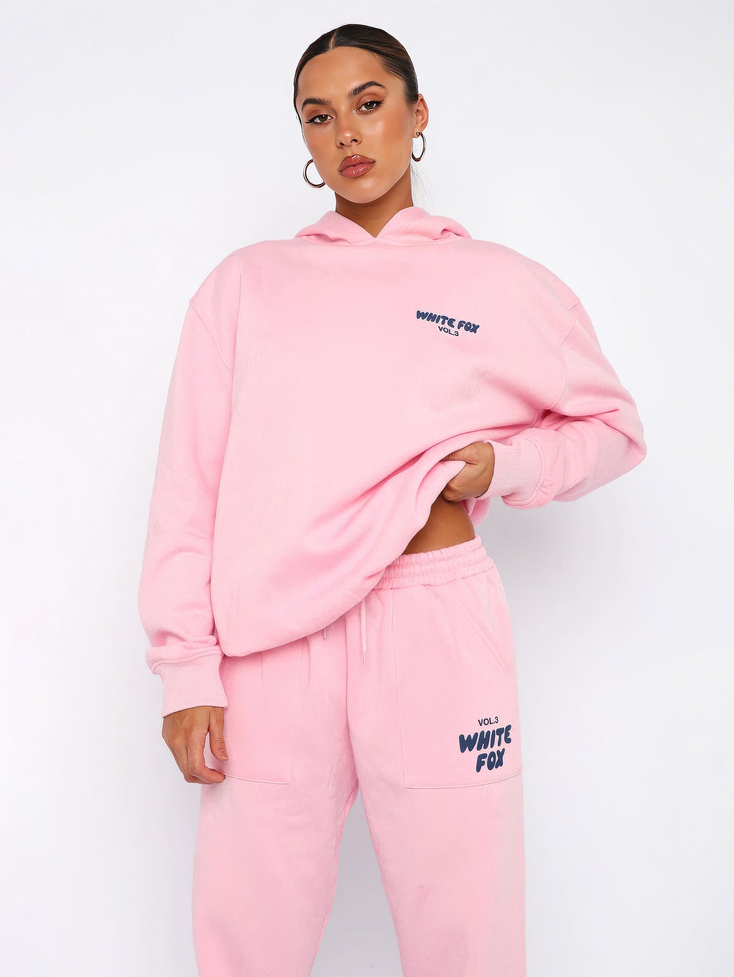 Frau in rosa Hoodie und Jogginghose, White Fox Logo, Freizeitmode, bequeme Damenbekleidung.