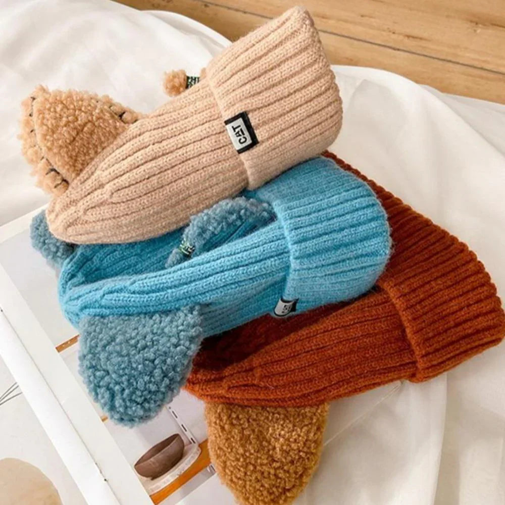 Drei gestrickte Mützen in Beige, Blau und Braun aus Wolle auf weißem Hintergrund.