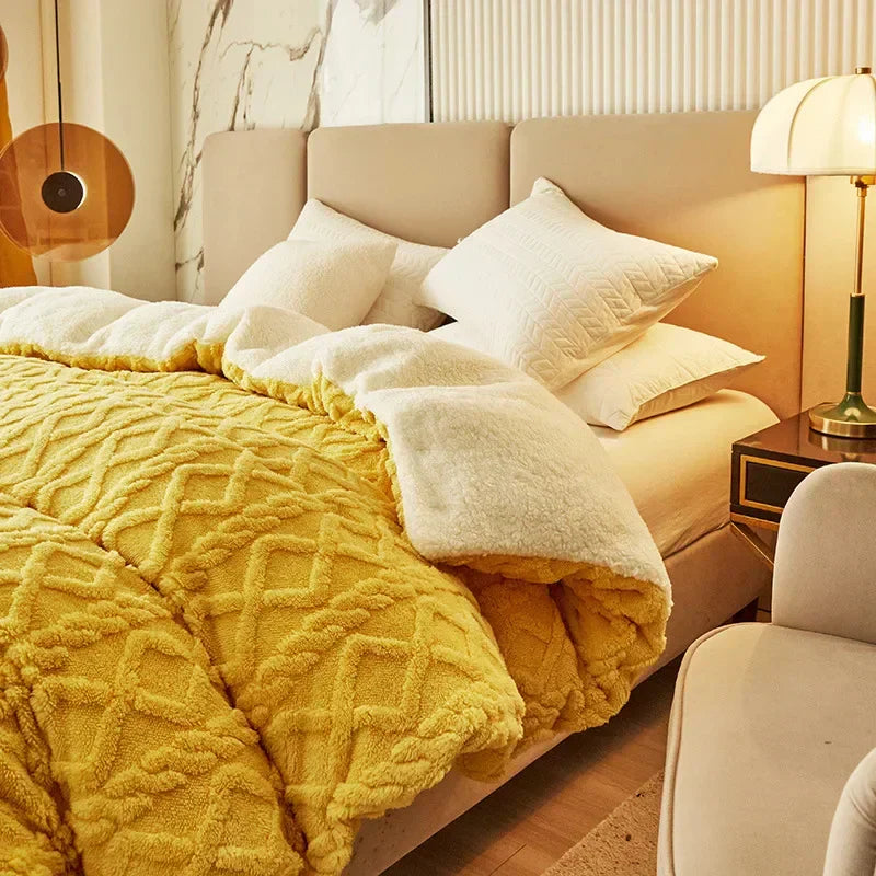 Gelbe Plüschdecke auf einem Bett mit beigen Kissen und Nachttischlampe im modernen Schlafzimmer.