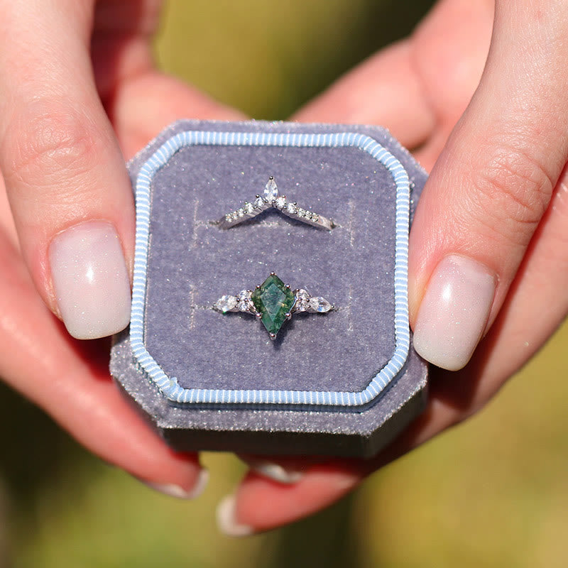 Silberner Verlobungsring mit Smaragd und Diamanten in blauer Schmuckschatulle, Nahaufnahme.