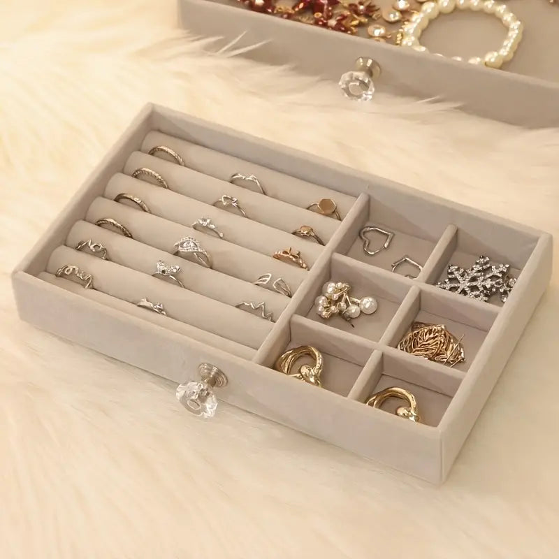 Beige Schmuck-Organizer aus Samt mit Fächern für Ringe und Ohrringe auf weißem Fell.