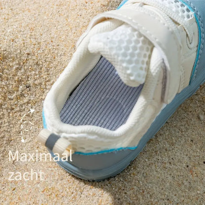 Weißer Kinderschuh mit Klettverschluss auf Sand, atmungsaktiv, bequem, ideal für Sommer.