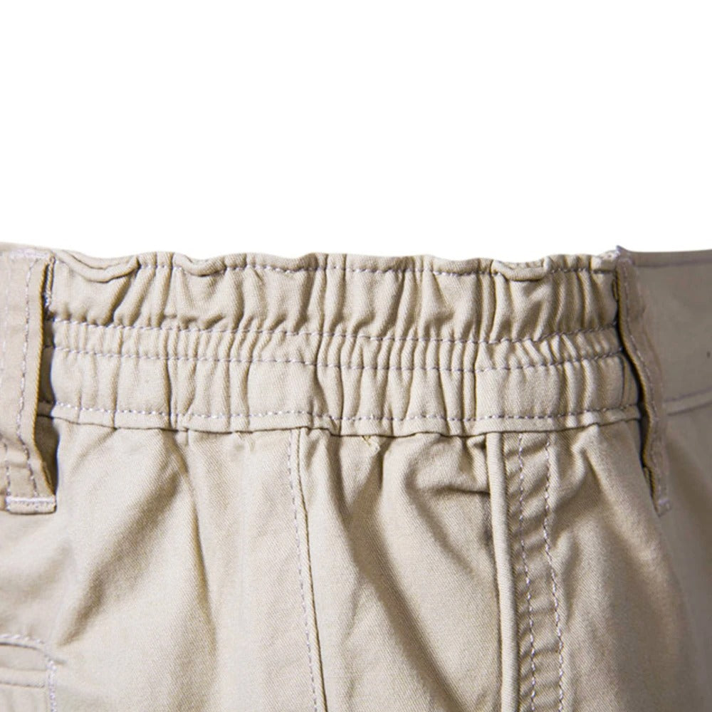 Närbild på shortsens resårmidja i beige med sömmar och skärmlinningsöglor. 4