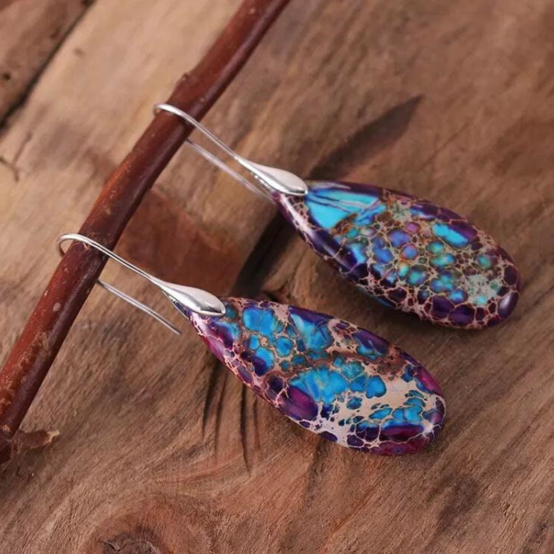 Blaue und violette Tropfen-Ohrringe aus Naturstein auf Holz, handgefertigter Schmuck.