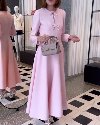 Frau in rosa Kleid mit Schleifen, hält graue Designer-Handtasche, Modegeschäft, elegant.