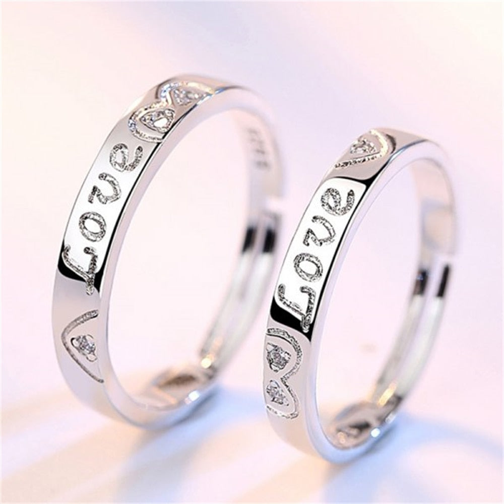 Silberne Partnerringe mit Gravur "Love" und Herzdesign, ideal als Verlobungs- oder Eheringe.