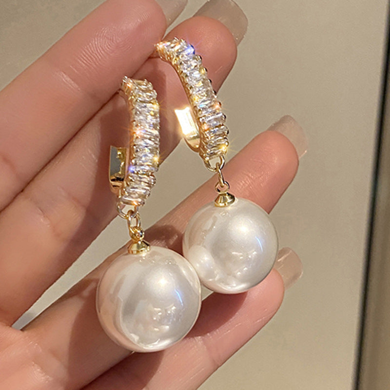 Goldene Ohrringe mit großen Perlen und Strasssteinen, eleganter Schmuck für Damen.
