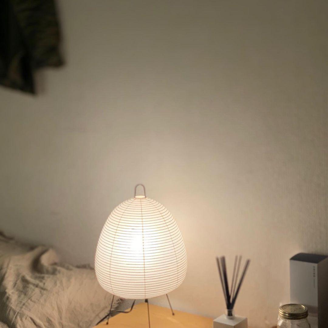 Weiße Akari Tischlampe auf Holzoberfläche, modernes Design, sanftes Licht, minimalistischer Stil.