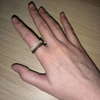 Hand mit Y2K-Stil Acrylharzring, beige, koreanische Mode 2023, auf Holzoberfläche.