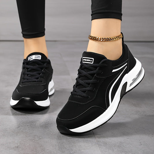 Närbild framifrån och snett från sidan på svarta snörade sneakers med vit sula, burna av en modell i svarta leggings. 2