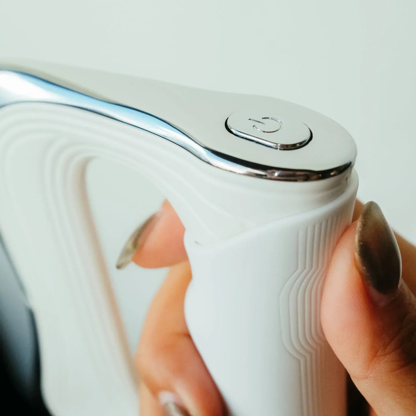 Weiße elektrische Zahnbürste mit silbernem Knopf, ergonomisches Design, Nahaufnahme.