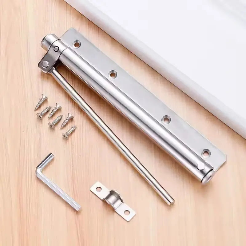 Silverfärgad dörrstängare med monteringsskruvar, insexnyckel och fäste liggande på en träskiva 6