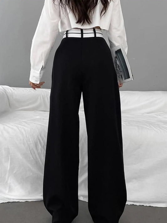 Frau in schwarzer Hose und weißer Bluse, hält Buch, moderne Mode, eleganter Look.