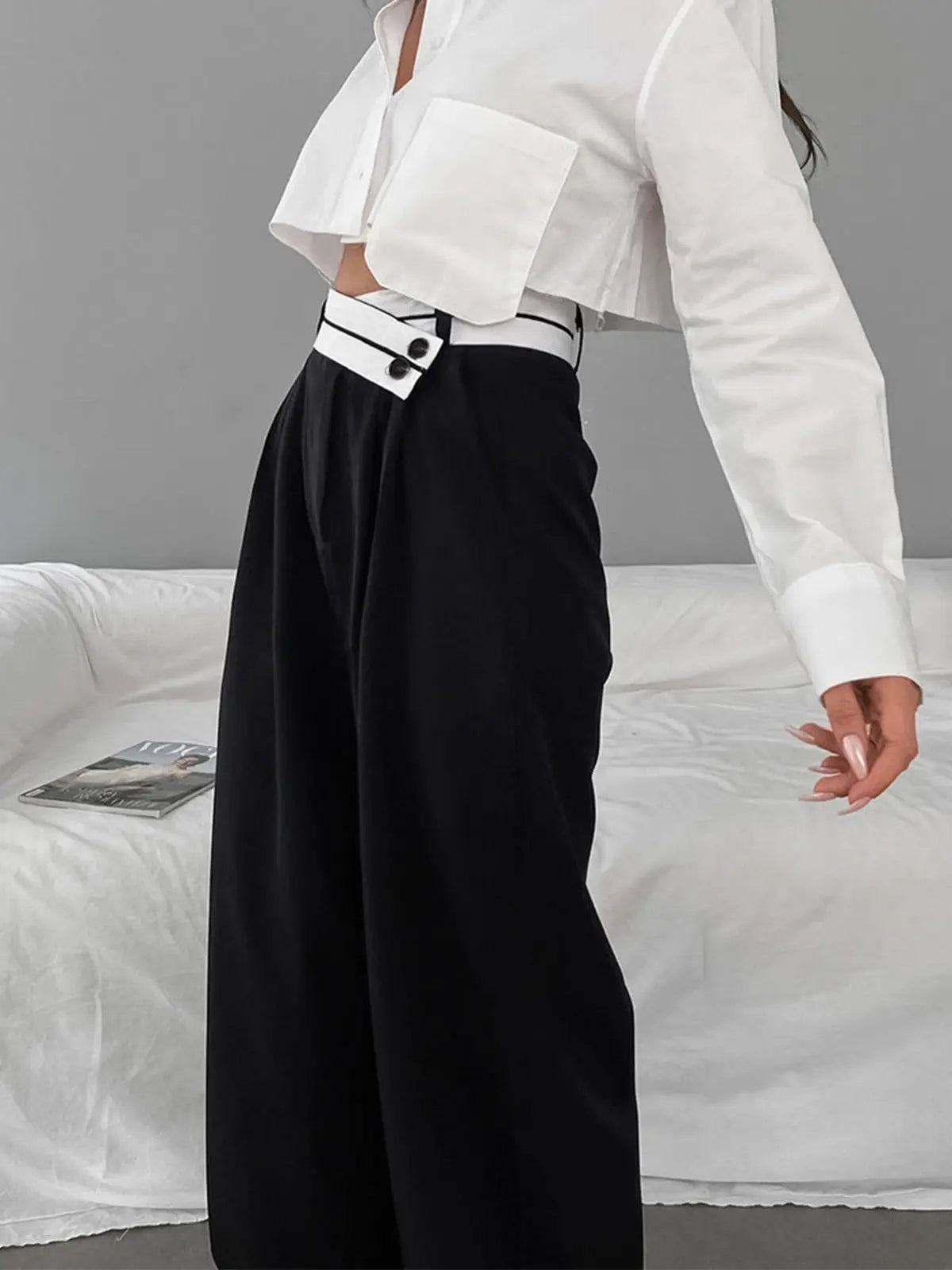 Frau in weißer Bluse und schwarzer Hose, moderne Mode, eleganter Stil, Wohnzimmer.