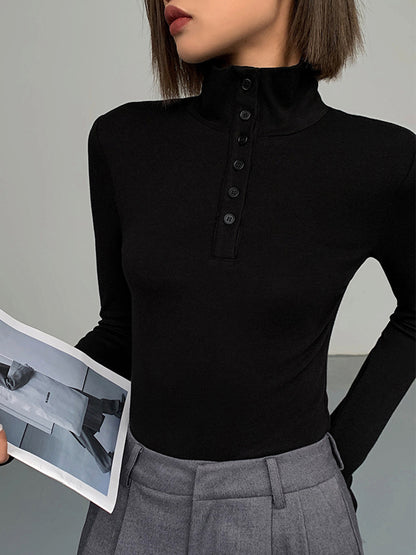 Frau in schwarzem Rollkragenpullover mit Knopfleiste, graue Hose, hält ein Foto.