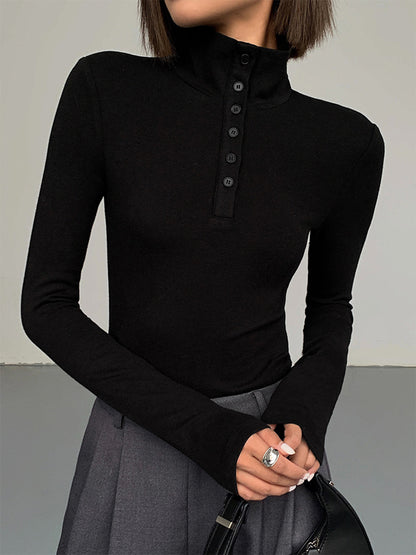 Frau in schwarzem Rollkragenpullover mit Knopfleiste, grauer Rock, eleganter Look.