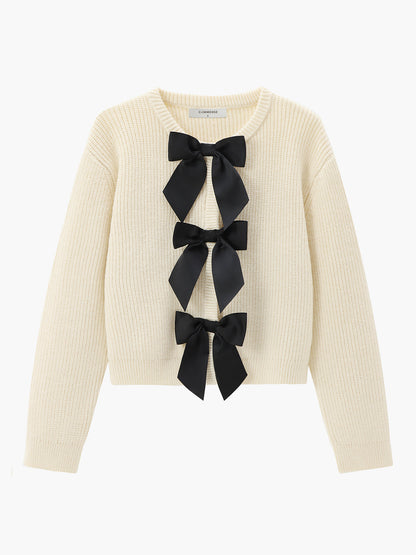 Cremefarbener Strickpullover mit schwarzen Schleifen, Damenmode, eleganter Herbst-Look.