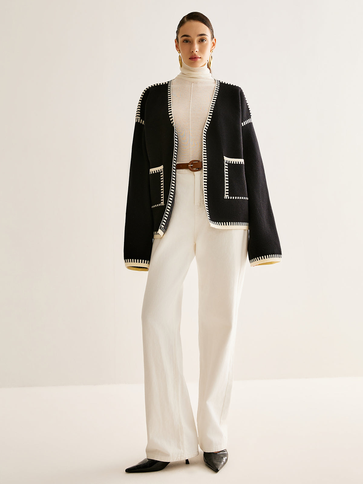 Frau in schwarzer Strickjacke und weißer Hose, elegantes Outfit, Mode, Damenbekleidung.