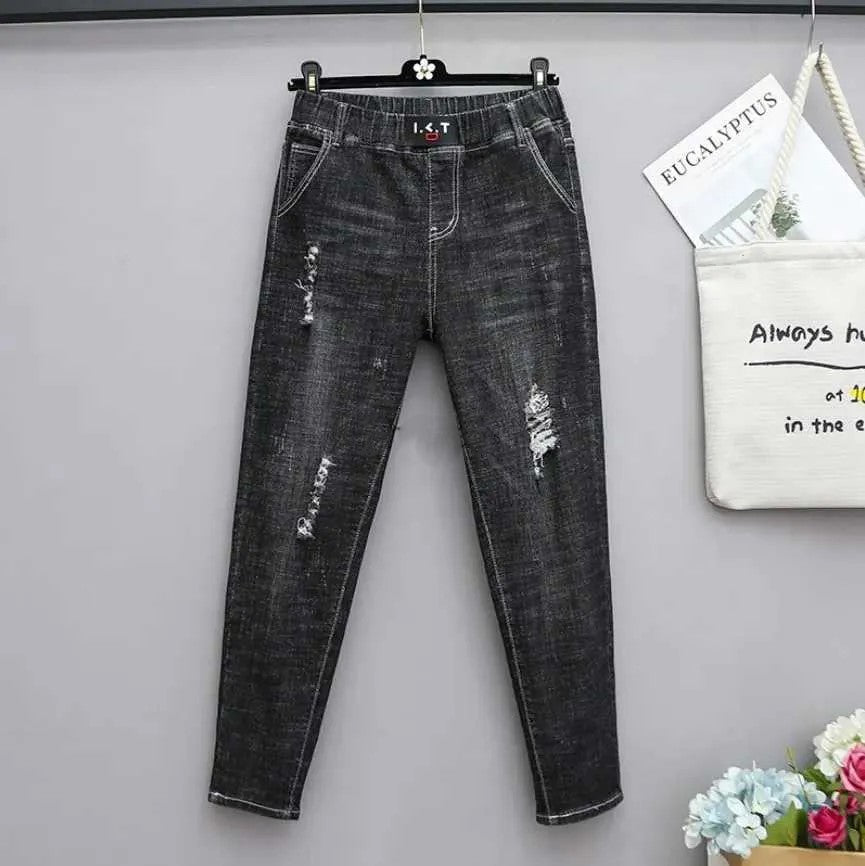 Schwarze Damenjeans, Slim Fit, zerrissen, Denim, modisch, lässig, hängend an grauer Wand.