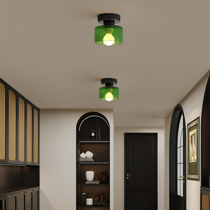 Två takspotlights med svart fäste och grön glasskärm lyser i en mörk hall med bågformade nischer och svarta dörrar. 4