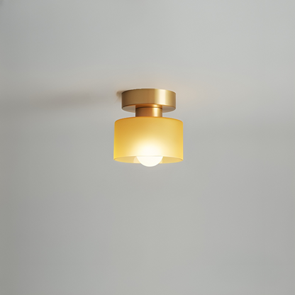 Takspotlight med guldfärgat fäste och gul frostad glasskärm, tänd glödlampa, mot ljusgrå bakgrund. 9