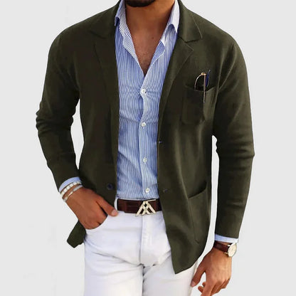 Herren Strickjacke in Olivgrün, kombiniert mit blau-weiß gestreiftem Hemd und weißer Hose.