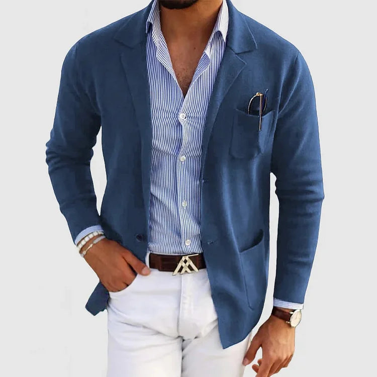 Mann in blauer Strickjacke, gestreiftem Hemd, weißer Hose; elegante Herrenmode.