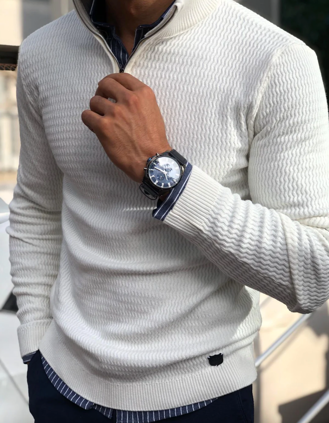Mann in weißem Strickpullover mit Armbanduhr, eleganter Herrenmode, stilvoller Look.