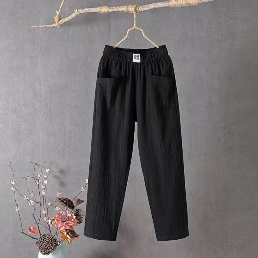 Schwarze Damenhose aus Baumwolle, elastischer Bund, lässiger Stil, hängend an Ast.