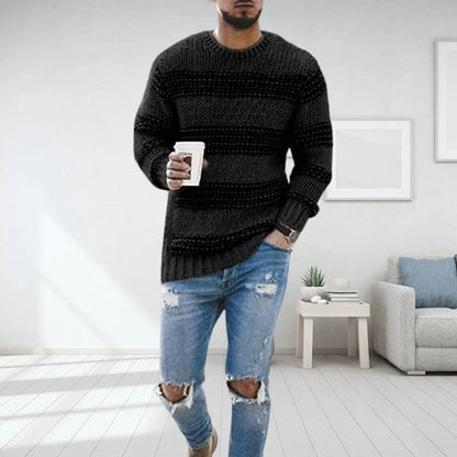 Mann in schwarzem Strickpullover und zerrissenen Jeans, hält Kaffeetasse, modernes Wohnzimmer.
