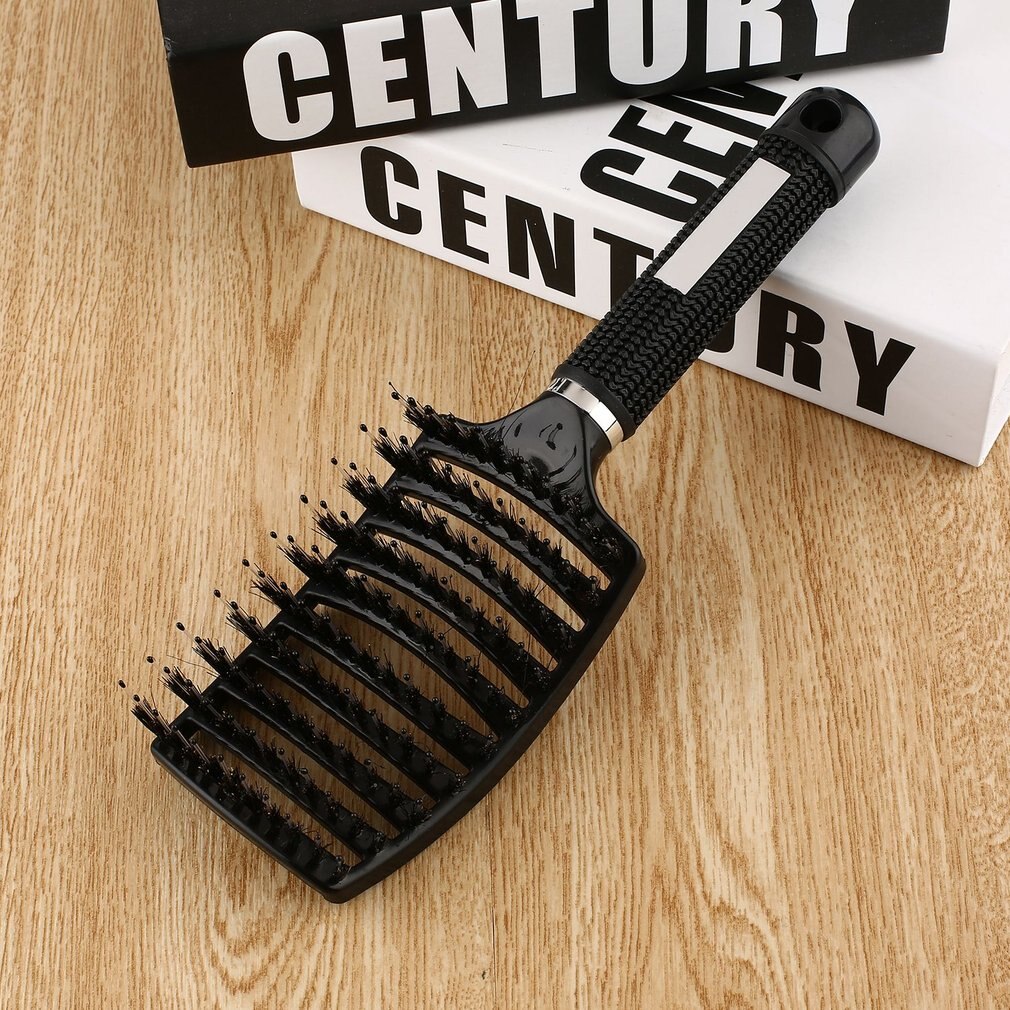 Schwarze Haarbürste mit ergonomischem Griff auf Holztisch, ideal für Styling und Entwirren.