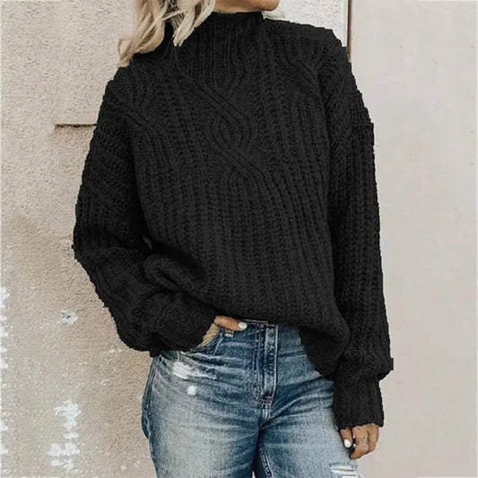 Frau in schwarzem Strickpullover und blauer Jeans vor beiger Wand.